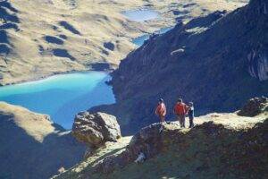 Two hikers admiring the picturesque view of a lagoon from the summit of a mountain